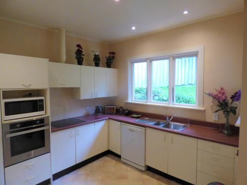 uma cozinha com armários brancos, um lavatório e uma janela em Sahara Deluxe Studios em Dunedin