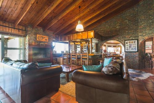 a living room with two leather couches and a fireplace at Melkbos Beach Lodge in Cape Town