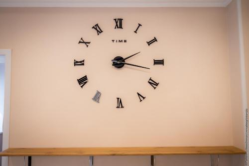 a wall clock with roman numerals on a wall at AS Inn Hotel in Karagandy