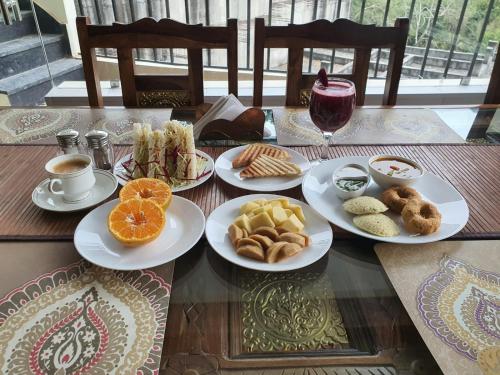 a table with plates of food and cups of coffee at Yogved Hospitality & Resort in Rishīkesh