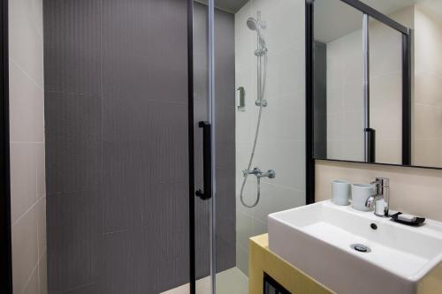 uma casa de banho com um chuveiro, um lavatório e um espelho. em Modena by Fraser Hong Kong em Hong Kong