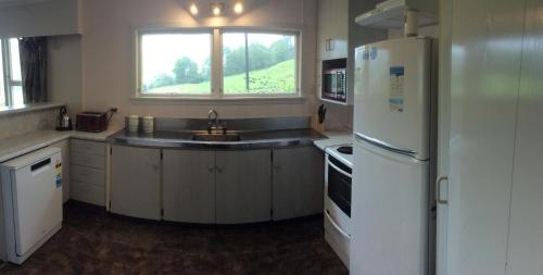 a kitchen with a sink and a white refrigerator at Hill top view farm stay in Uruti