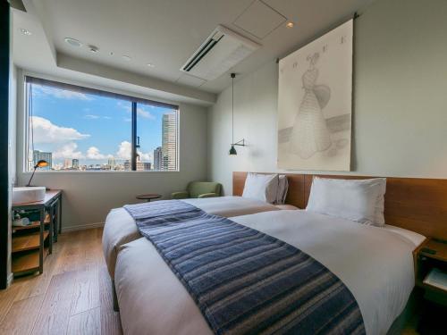 sypialnia z dużym łóżkiem i dużym oknem w obiekcie Ebisuholic Hotel w Tokio