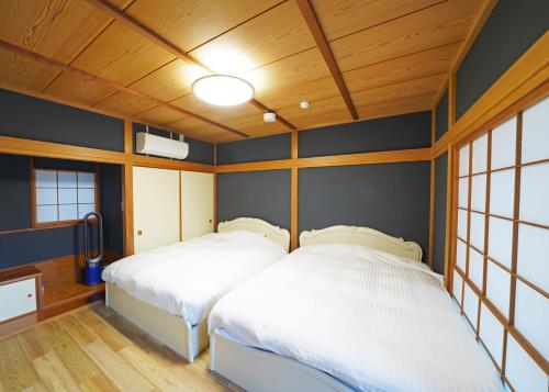 two beds in a room with blue walls and wooden ceilings at Villa Liberte Hakone Gora in Hakone