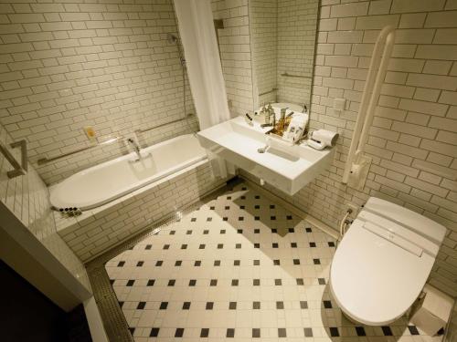 a white bathroom with a toilet and a sink at Ebisuholic Hotel in Tokyo