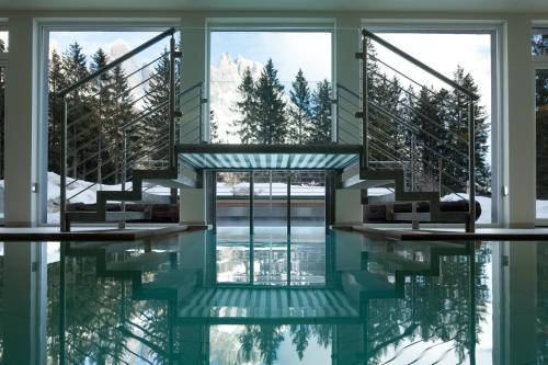 a swimming pool with a stair in the middle of a building at Sayonara Nature & Wellness Hotel in San Martino di Castrozza