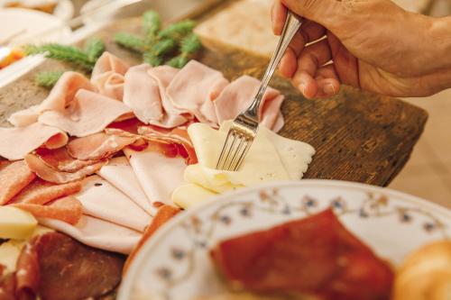 a person is cutting meat with a fork and knife at Sayonara Nature & Wellness Hotel in San Martino di Castrozza