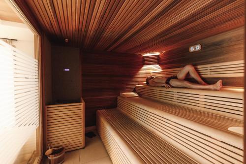 a man is laying in a sauna at Sayonara Nature & Wellness Hotel in San Martino di Castrozza