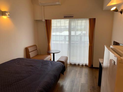 a bedroom with a bed and a chair and a window at Clean Hotels in Higashimachi in Naha