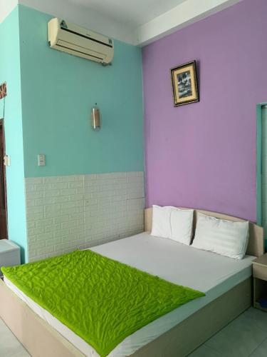 Happy Hotel Binh Tan في مدينة هوشي منه: سرير في غرفة أرجواني وأزرق