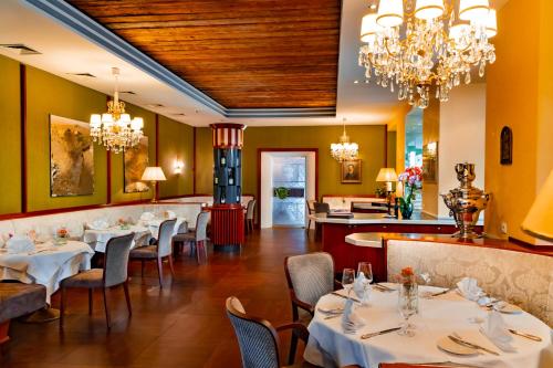 a dining room with tables and chairs and chandeliers at Parkhotel Graz - Traditional Luxury in Graz