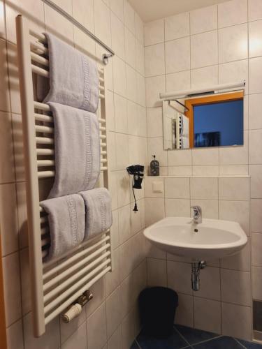 a white bathroom with a sink and towels at Frühstückspension Klein und Fein in Bad Hofgastein