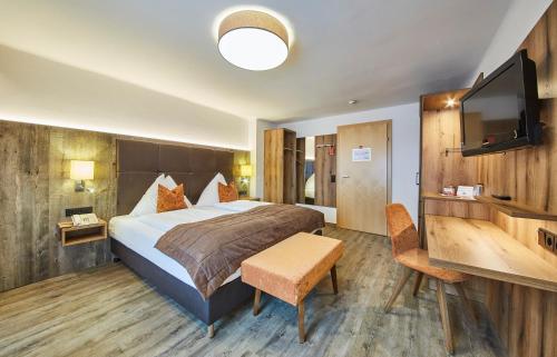 a hotel room with a bed and a flat screen tv at Hotel Römerhof in Fusch an der Glocknerstraße