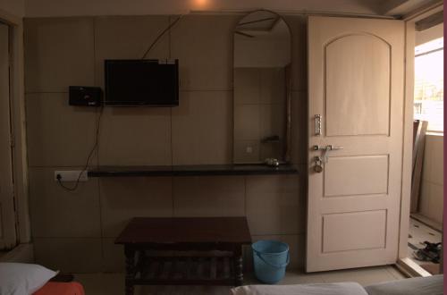 a room with a door and a table and a television at Mourya Deluxe A/C Lodge in Chitradurga