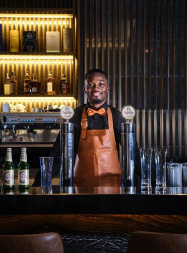 a man in an apron standing behind a bar at K Hotel Douala in Douala