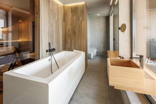 a large white bath tub in a bathroom at Qosmo Brasov Hotel in Braşov