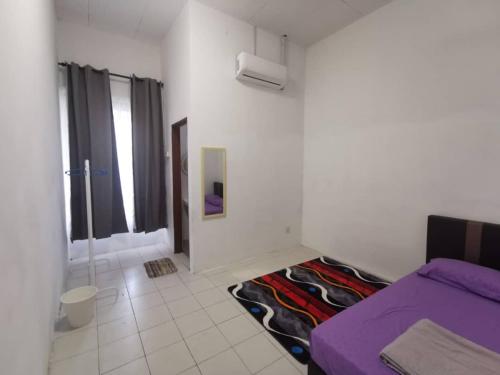 a bedroom with a purple bed and a bathroom at AS'CATTLEYA HOMESTAY in Sepang