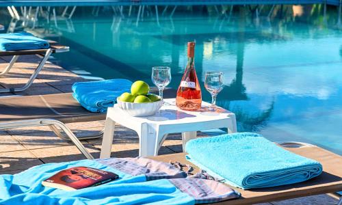 a table with a bottle of wine and glasses next to a pool at Welcome Apts in Georgioupolis