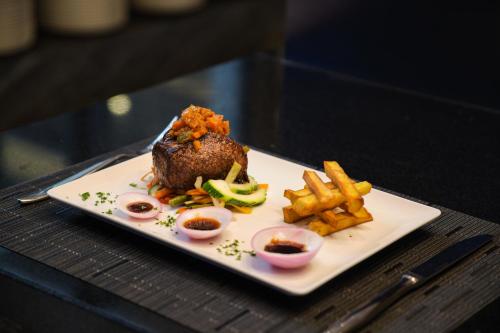 a plate of food with meat and fries on a table at K Hotel Douala in Douala