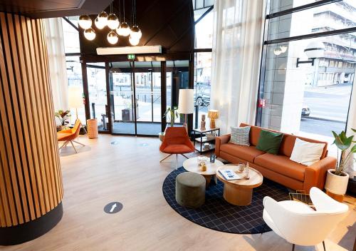 a living room with a couch and tables and chairs at Kyriad Prestige Hotel Clermont-Ferrand in Clermont-Ferrand