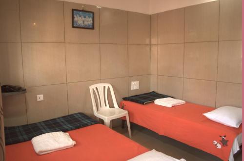 una camera con due letti e una sedia bianca di Mourya Deluxe A/C Lodge a Chitradurga