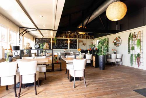 un restaurante con mesas y sillas blancas en una habitación en TopParken – Recreatiepark het Esmeer, en Aalst