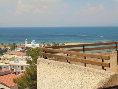 斯卡拉的住宿－阿基斯提島夢幻酒店，坐在墙上的长凳上,望着大海