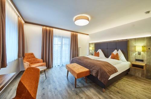 a hotel room with a bed and two chairs at Hotel Römerhof in Fusch an der Glocknerstraße
