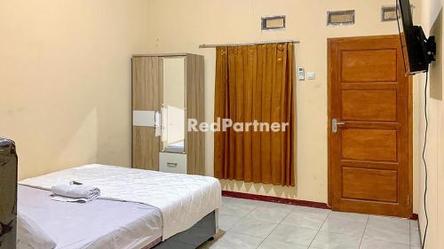 um quarto com uma cama e uma porta de madeira em PSM Syariah Guest House RedPartner em Raab