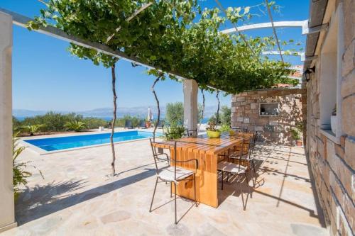 a wooden table and chairs on a patio with a pool at Holiday Home My Summer House in Supetar