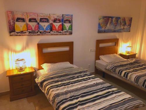 dwa łóżka w pokoju z obrazami na ścianie w obiekcie Duquesa Norte, Vistalmar Sea View Panorama w mieście Castillo de Sabinillas