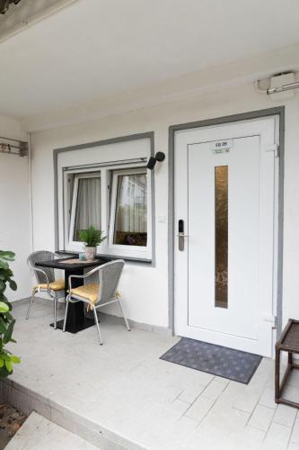 eine weiße Tür auf einer Terrasse mit einem Tisch und Stühlen in der Unterkunft Apartment EG 09 in Darmstadt