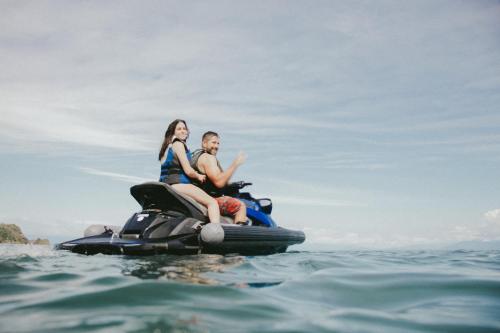 a man and woman riding a jet ski on the water at Surf Synergy All-Inclusive Surf and Wellness Retreat in Jacó