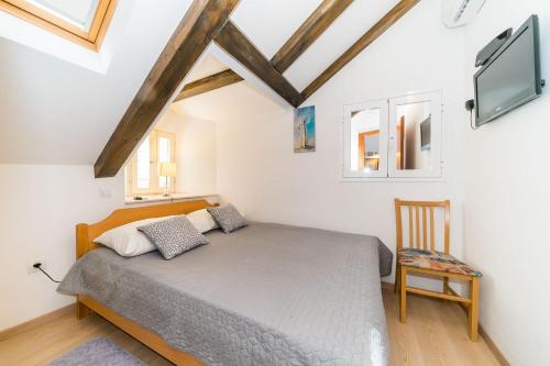um quarto com uma cama, uma televisão e uma cadeira em Holiday Home Kazerma em Dubrovnik