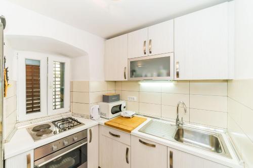 a kitchen with white cabinets and a sink and a microwave at Holiday Home Kazerma in Dubrovnik