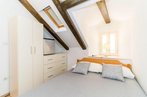 a bedroom with white walls and a bed with two pillows at Holiday Home Kazerma in Dubrovnik