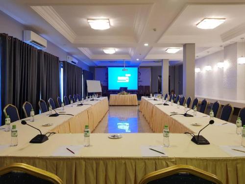 a conference room with tables and chairs and a screen at KEP BAY HOTEL & RESORT in Kep