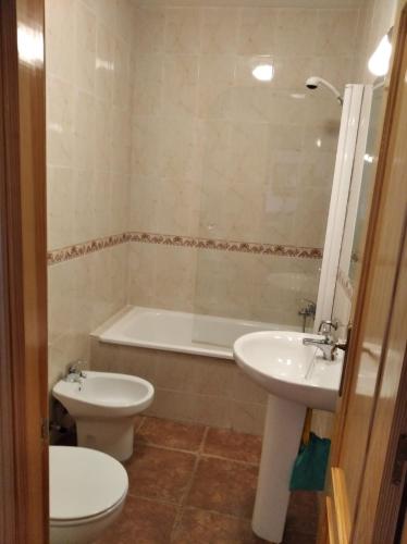 a bathroom with a toilet and a sink and a tub at Casa Rural el Maestro II in Navalosa