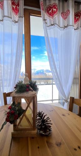 uma mesa com decorações de Natal em frente a uma janela em Superbe appartement à 50m des pistes parking privé em La Toussuire