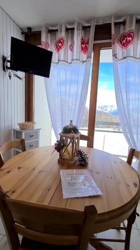 a wooden table in a room with a large window at Superbe appartement à 50m des pistes parking privé in La Toussuire
