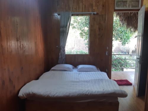 a bed in a wooden room with a window at Your home Mai Chau in Mai Chau