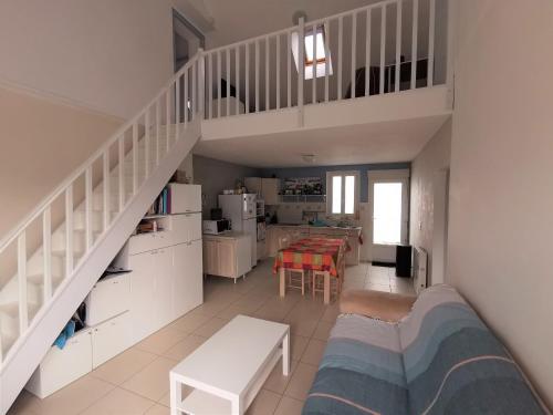 un salon avec un escalier et une cuisine dans l'établissement L'Ecoliere, à Notre-Dame-de-Monts
