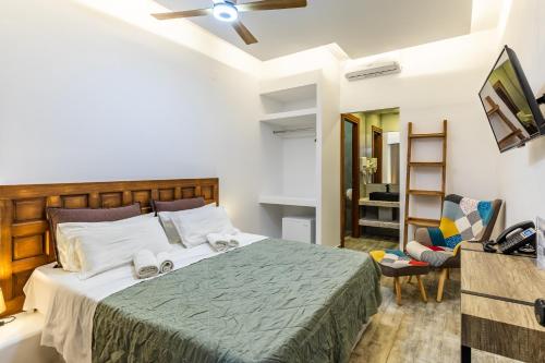 a bedroom with a bed and a tv and a chair at Rigas Hotel Skopelos in Skopelos Town