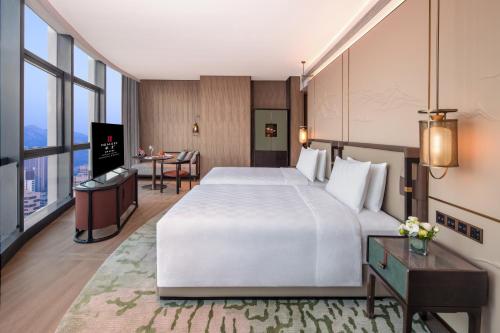 a hotel room with a large bed and a table at HUALUXE Hotels and Resorts Qingdao Licang in Qingdao