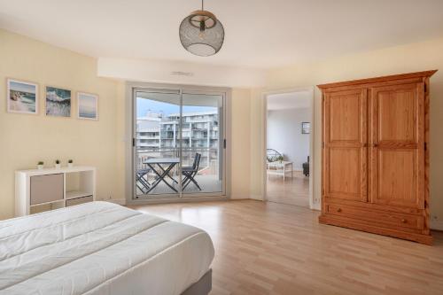 a bedroom with a bed and a balcony with a table at Tres bel appartement avec vue sur la mer a Pornichet in Pornichet
