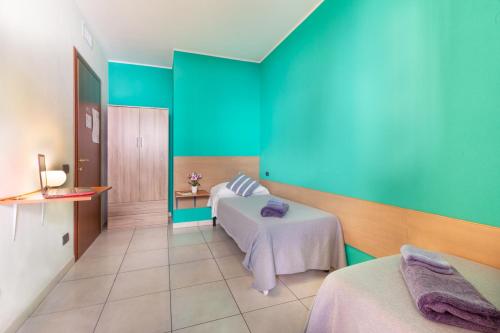 Cette chambre comprend 2 lits et un mur bleu. dans l'établissement Ogliastra Apartment Rooms, à Cagliari