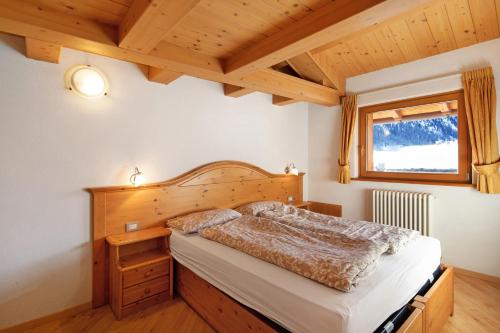 - une chambre avec un lit et un plafond en bois dans l'établissement Appartamento Cima Fopel, à Livigno