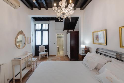 a bedroom with a large white bed and a chandelier at Hotel Rosa De oro in Granada
