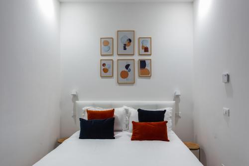 una camera da letto con un letto bianco con cuscini arancioni e blu di Correggio Fiera Suite a Milano