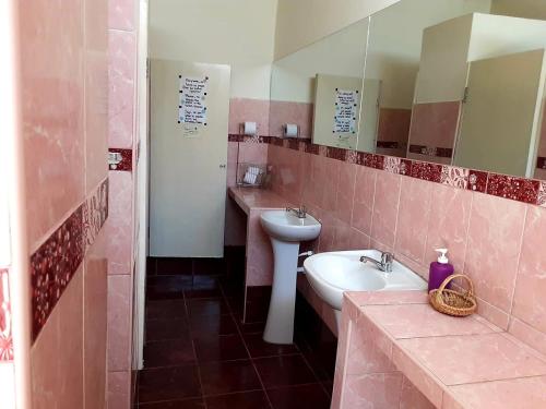 Baño rosa con lavabo y espejo en Hermosa Villa Hospedaje, en Trujillo